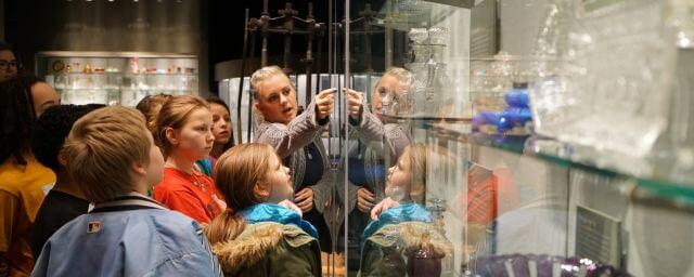Adult showing an item in a gallery to a group of children