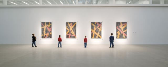 Four children stand in front of four colored glass wall panels