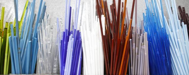 Colorful glass rods stand in labeled silver metal jars