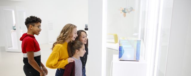 Group of kids looks at art in a white walled gallery