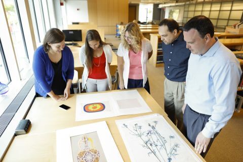 A group of people look at library archival materials on a table