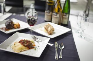 White plates with catered meal options: ravioli, chicken or steak with a variety of wines