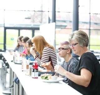 People sitting at a bar table eating lunch in the sunlight filled Museum Cafe